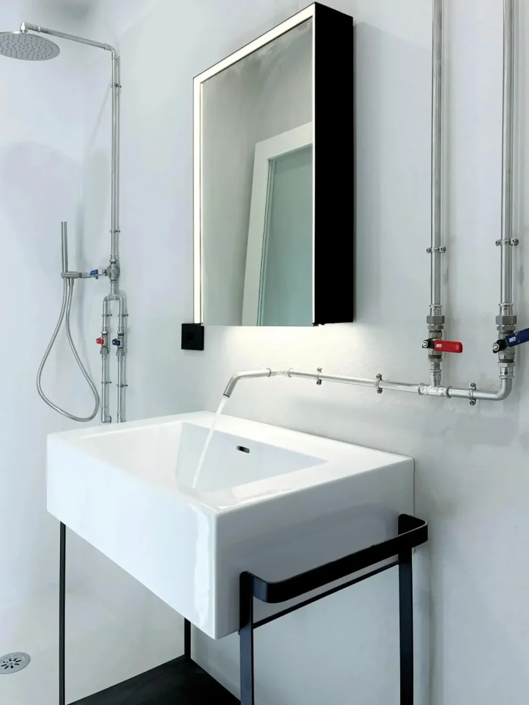 Bagno "stile industriale" con tubazione a vista geberit, con pareti in micro cemento color ghiaccio. Milano ripa di P.ta Ticinese